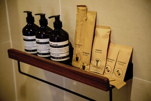 Une étagère avec trois bouteilles de savon liquide et trois sacs en papier avec du texte.