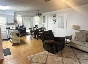 A spacious living room with a brown leather armchair, a beige sofa, and a dining area with a wooden table and chairs. - Comfortable Long-Term Rental Home in Gonzales (Gonzales)