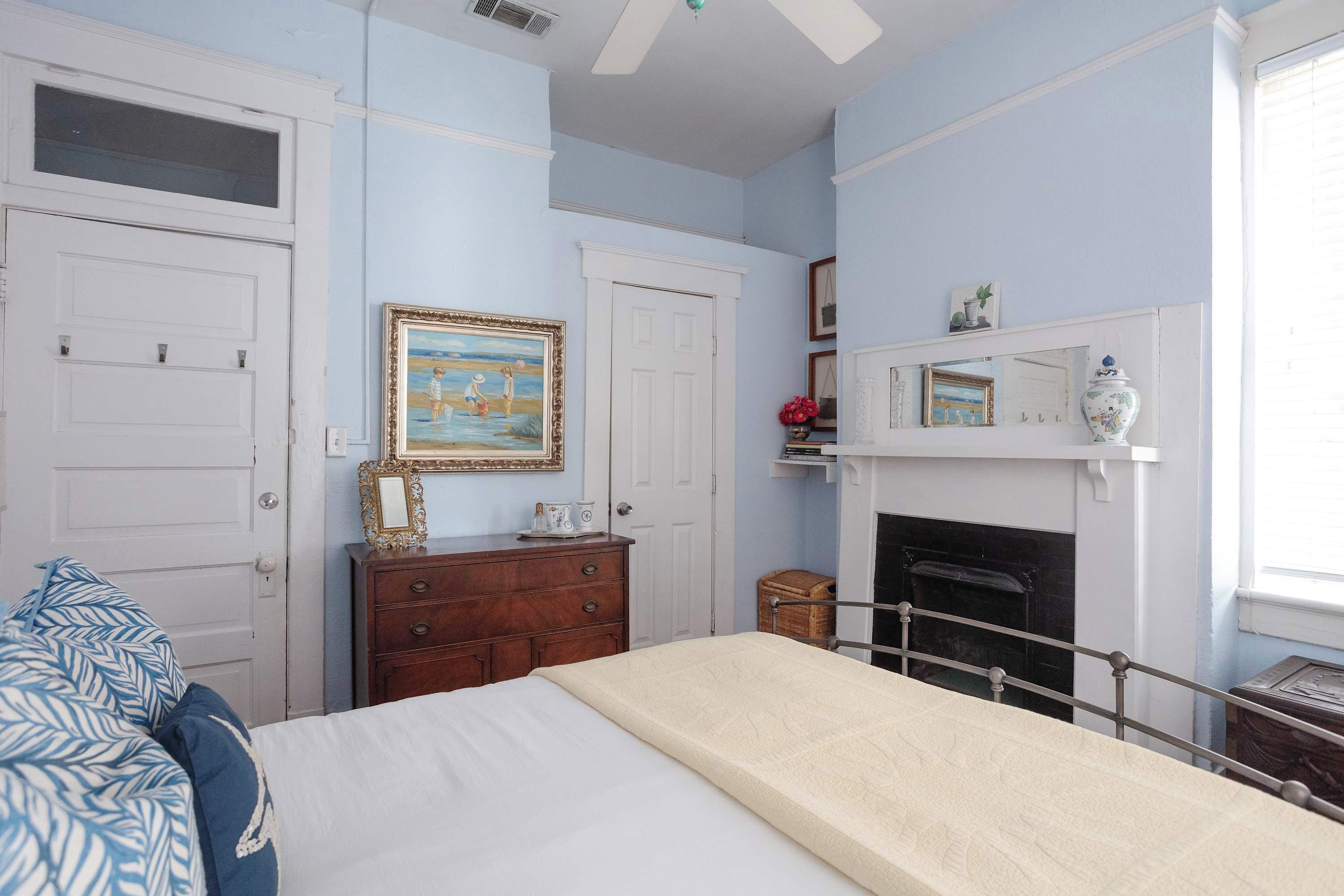A bedroom with a bed, dresser, and a fireplace.