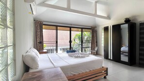 Ein Schlafzimmer mit einem großen Bett, einer Holzbank, einem Balkon mit Aussicht und einem Kleiderschrank.