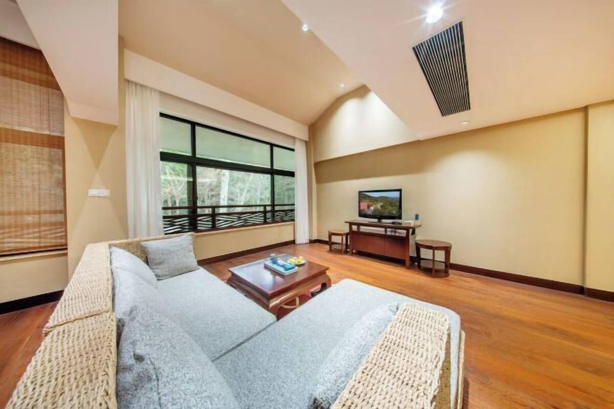 A modern living room with a sofa, TV, and wooden flooring.