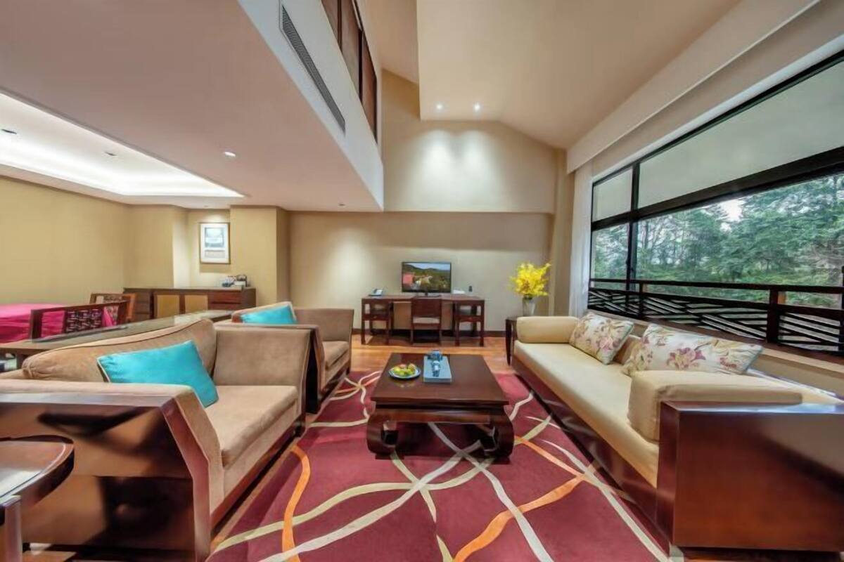 A modern living room with a sofa, armchairs, a coffee table, and a dining area with a table and chairs.