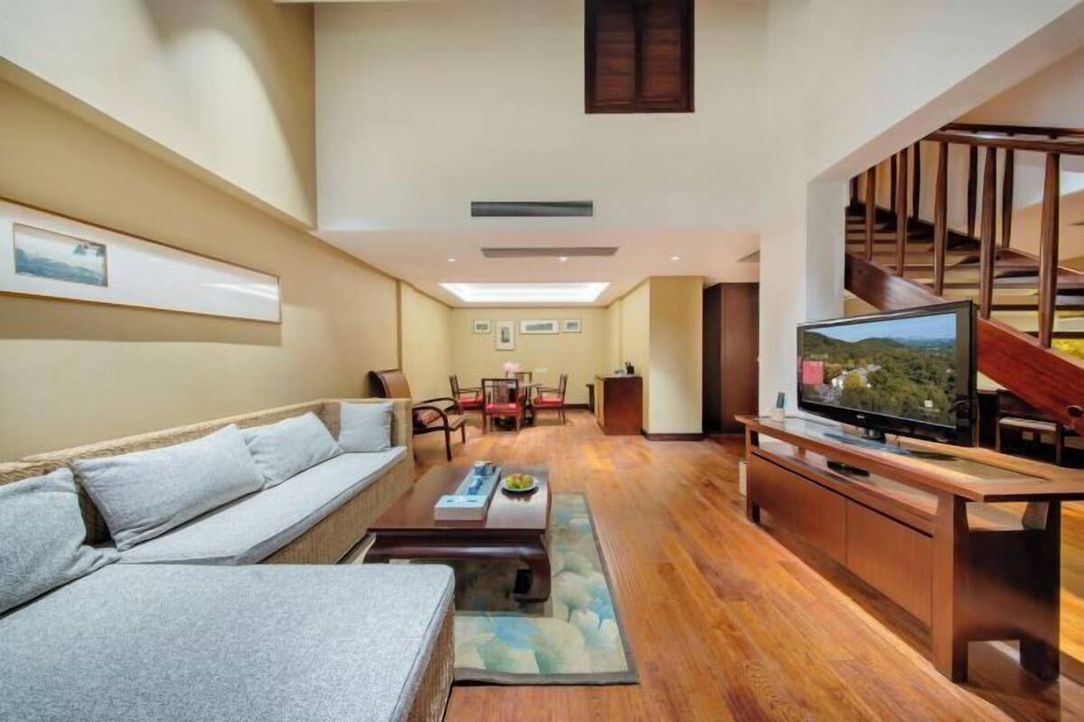 A modern living room with a sofa, coffee table, TV, and staircase.