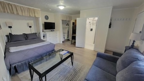 Een slaapkamer met een bed, een televisie, een bureau en een kledingkast.
