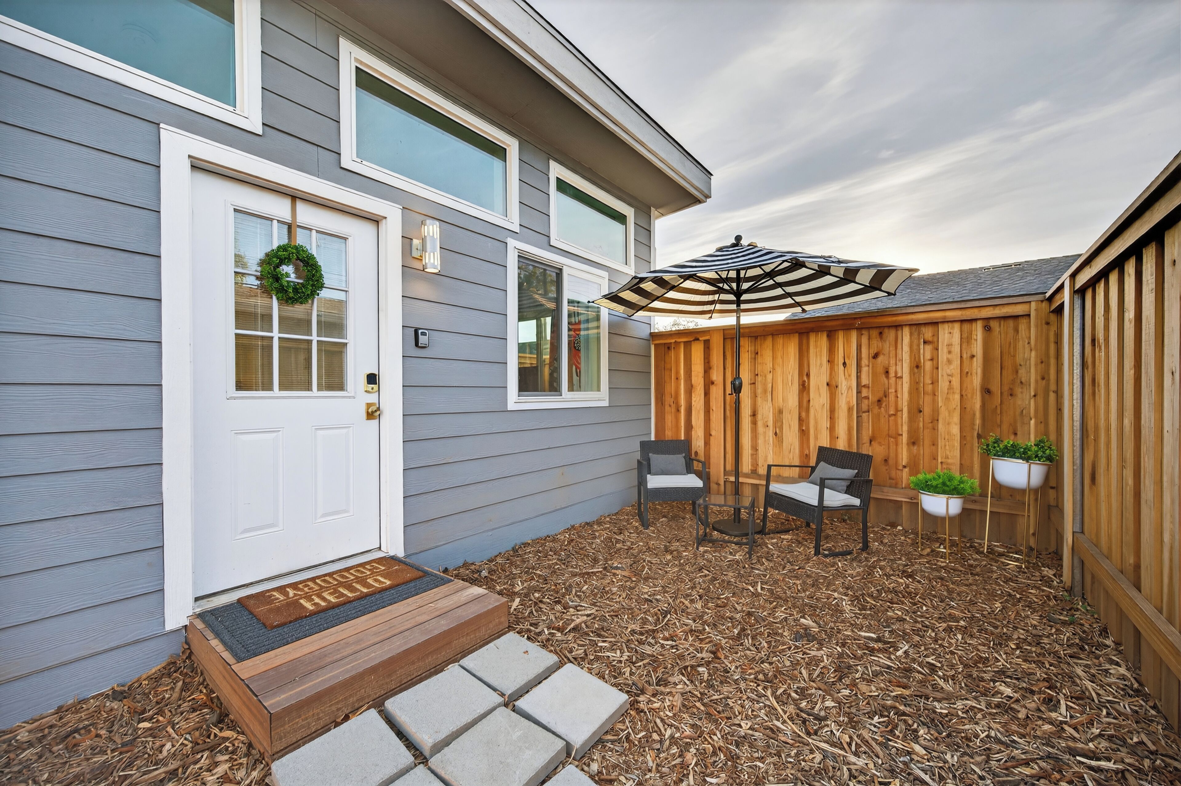 A house with a front door, a mailbox, a bench, and a wooden fence.