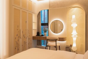 Une chambre à coucher comprenant un lit, un bureau avec une chaise, un miroir rond et une lampe fixée au mur.