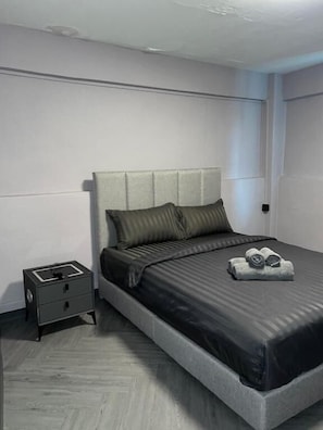 Ein modernes Schlafzimmer mit einem Bett, einem Nachttisch und einer Wandleuchte.