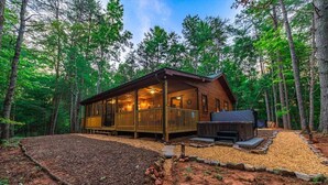 Eine Hütte mit einer Terrasse, einem Kamin und einem überdachten Sitzbereich im Grünen.