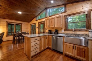 A wooden cabin interior with a kitchen, dining area, and large windows. - Brew Ridge | Blue Ridge, Ga (Blue Ridge)