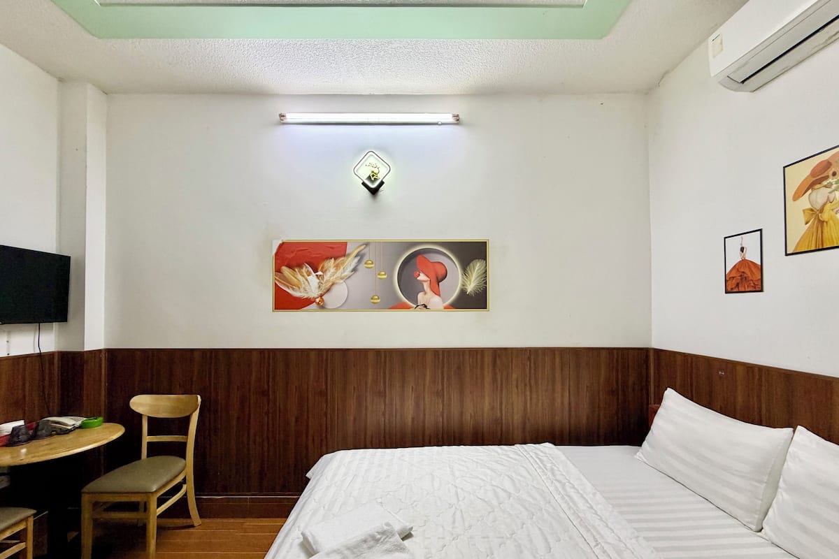 Habitación de hotel con cama, escritorio, silla, televisión de pantalla plana y obras de arte en la pared.