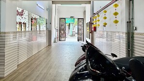 A hallway with tiled walls, a ceiling with a recessed light, and a motorcycle parked on the right. - Hoa Nang Mai Hotel (Ho Chi Minh City)