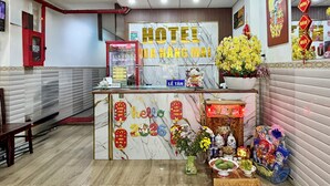 A hotel reception desk with a marble wall, a Coca-Cola refrigerator, and a sign that reads 'HOTEL ĐÀNG MÀI'. - Hoa Nang Mai Hotel (Ho Chi Minh City)
