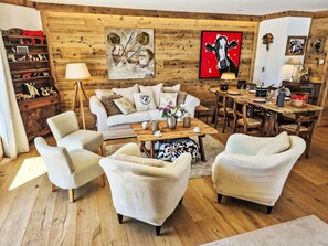 Ein gemütliches Wohnzimmer mit einer Couch, Sesseln, einem Couchtisch und einer Holzwand.