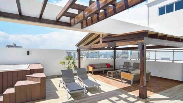 A rooftop terrace with a wooden pergola, seating area, and a view of the city skyline. - Luxurious 3-bedroom Condo With City Views in Santo Domingo (Santo Domingo)