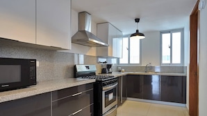 A modern kitchen with a built-in microwave, stove, and coffee maker. - Luxurious 3-bedroom Condo With City Views in Santo Domingo (Santo Domingo)