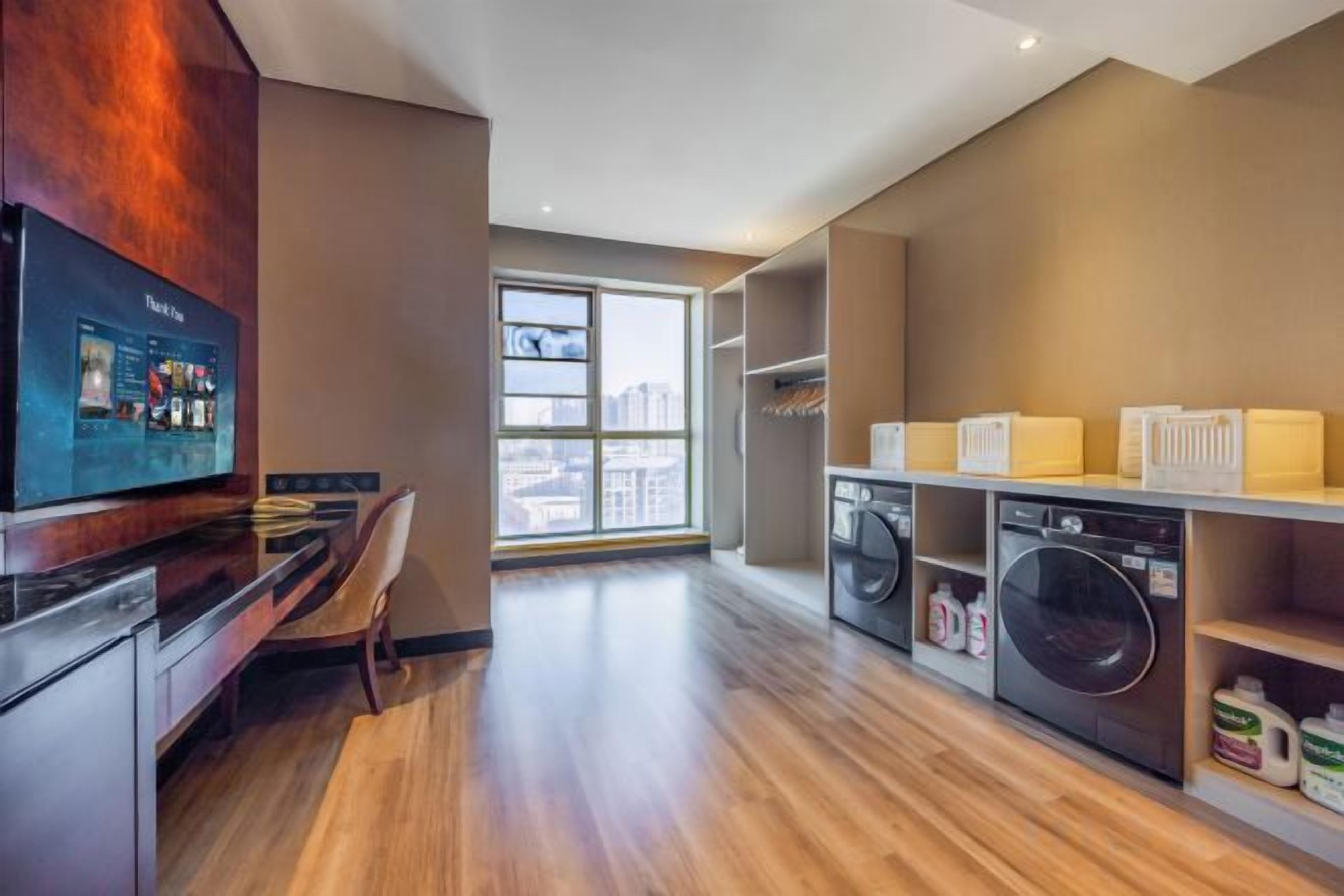 Una cocina moderna con televisor de pantalla plana, suelo de madera y un ventanal con vistas a la ciudad.