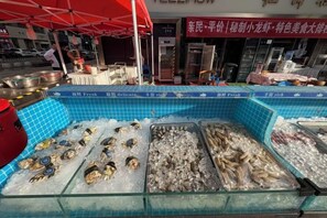 A seafood display at a market stall with ice, fresh seafood, and a red umbrella. - The Royal International Hotel (Ordos)