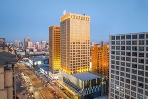A high-rise building with a prominent corner entrance and a large glass facade. - The Royal International Hotel (Ordos)