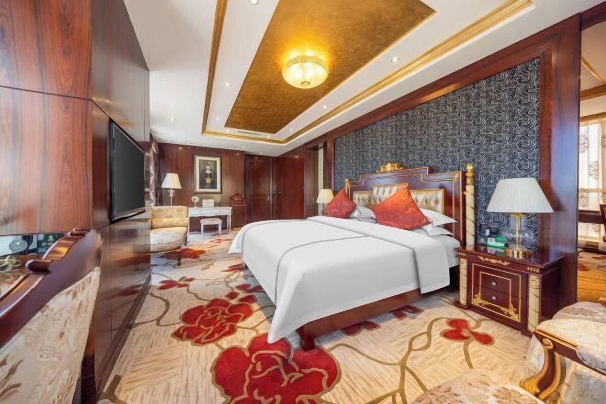 A hotel room with a large bed, a TV, a desk, and a chair.