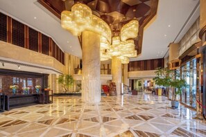 A spacious lobby with a high ceiling, large columns, and a geometric floor pattern. - The Royal International Hotel (Ordos)