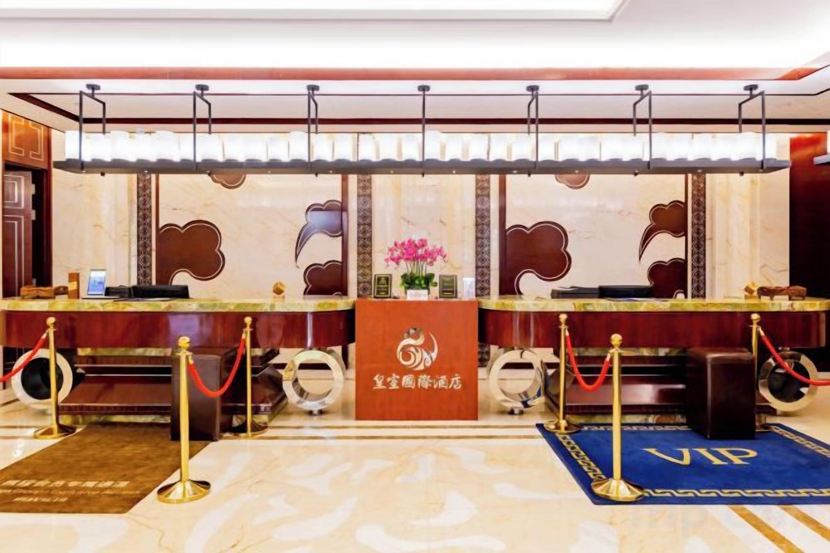 Un espace d’accueil d’hôtel comprenant un comptoir en marbre, un espace réservé aux clients VIP et un bureau d’accueil.