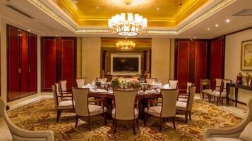 A formal dining room with a chandelier, a large table set for six, and red paneling on the walls.