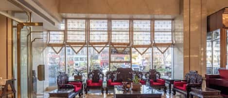 A spacious lobby with a high ceiling, large windows, and a variety of seating arrangements.