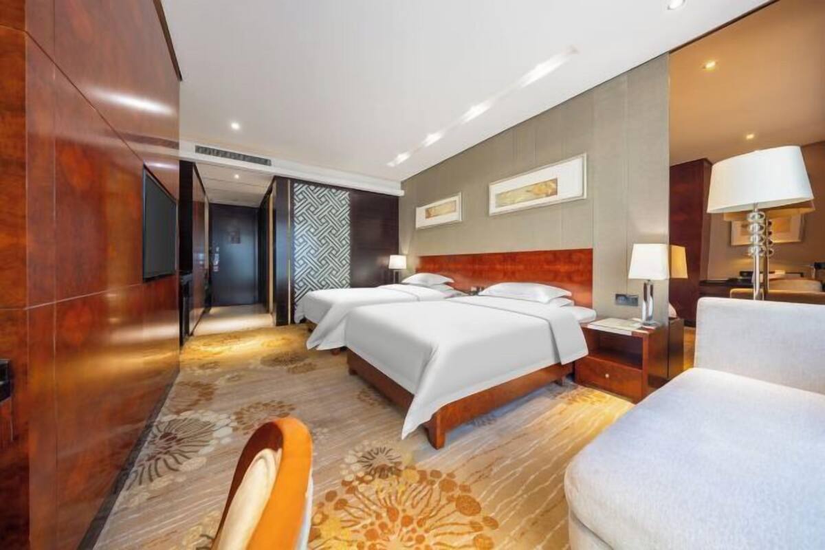 A hotel room with a large bed, two bedside tables, a desk, and a chair.