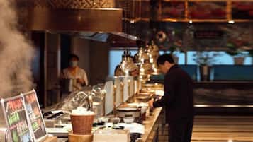 A restaurant interior with a long counter, steam rising from the stove, and a person working in the background.