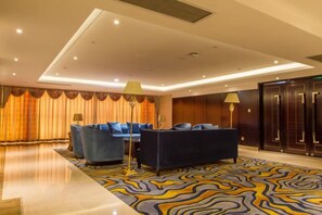 A hotel lobby with a blue sofa set, a patterned carpet, and a large mirror. - The Royal International Hotel (Ordos)