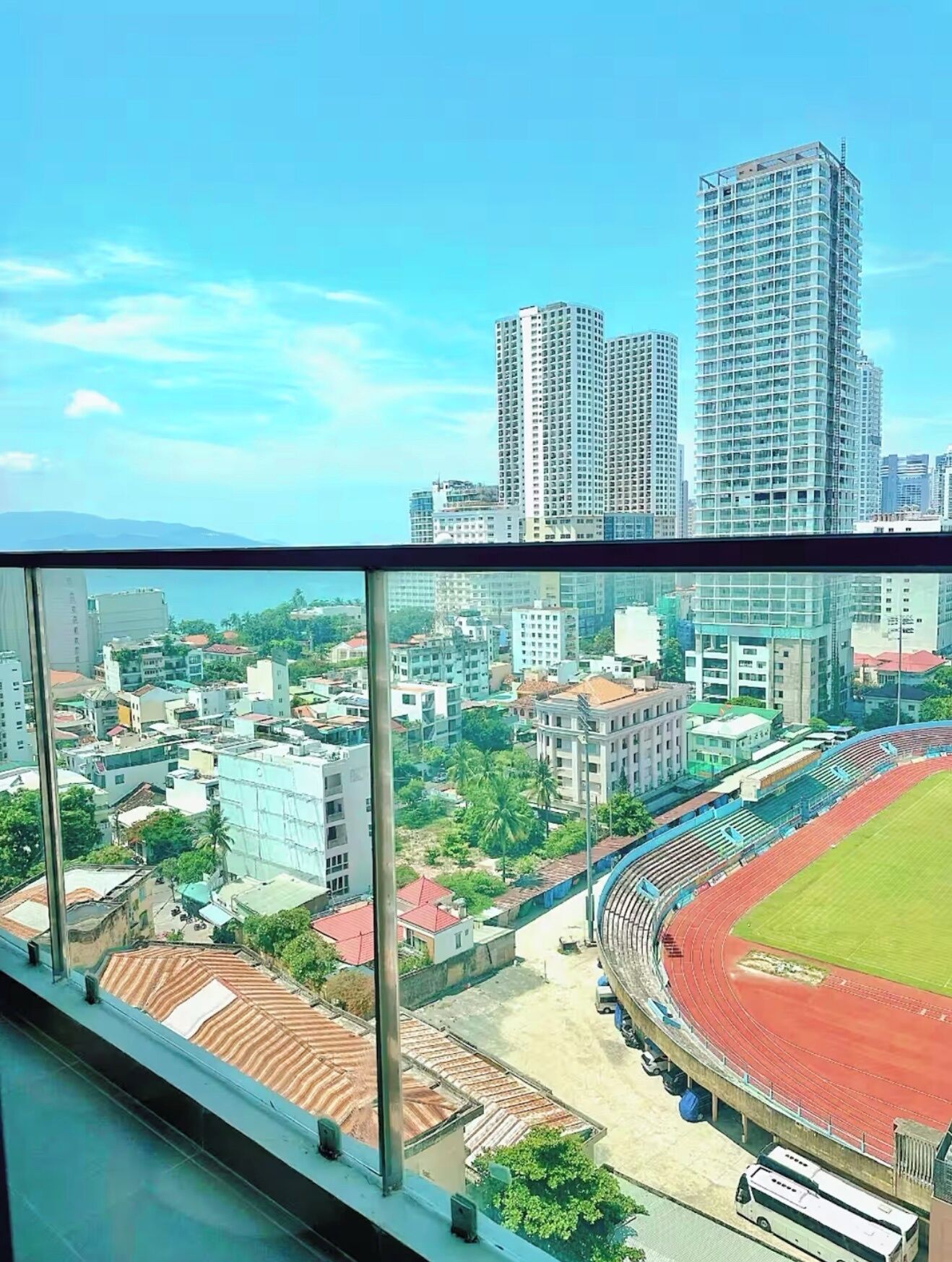 A high-rise building with a view of a stadium and surrounding urban area.
