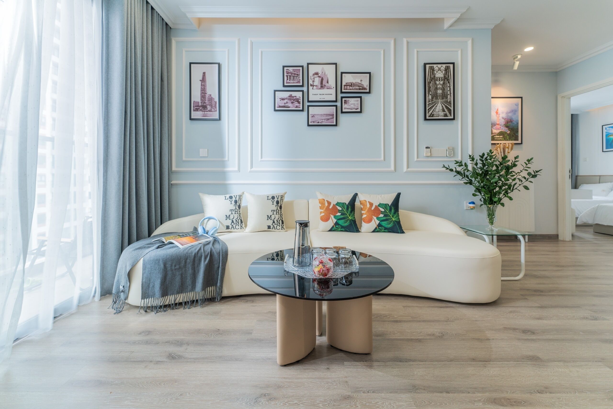 A modern living room with a curved sofa, a round coffee table, and framed pictures on the wall.