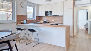 A modern kitchen with a central island, bar stools, and a dining table. - Apartment Karlo by Interhome (Pag/Povljana)