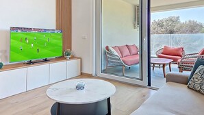 A modern living room with a flat-screen TV, a round table, and a sofa. - Apartment Karlo by Interhome (Pag/Povljana)