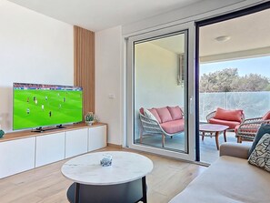 Ein modernes Wohnzimmer mit Flachbildfernseher, einem runden Tisch und einer Couch.