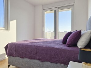 Ein Schlafzimmer mit Bett, Kissen, einem Nachttisch und einem Fenster.