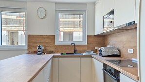 A modern kitchen with a wooden countertop, a built-in oven, and a window with a view of construction outside. - Apartment Karlo by Interhome (Pag/Povljana)
