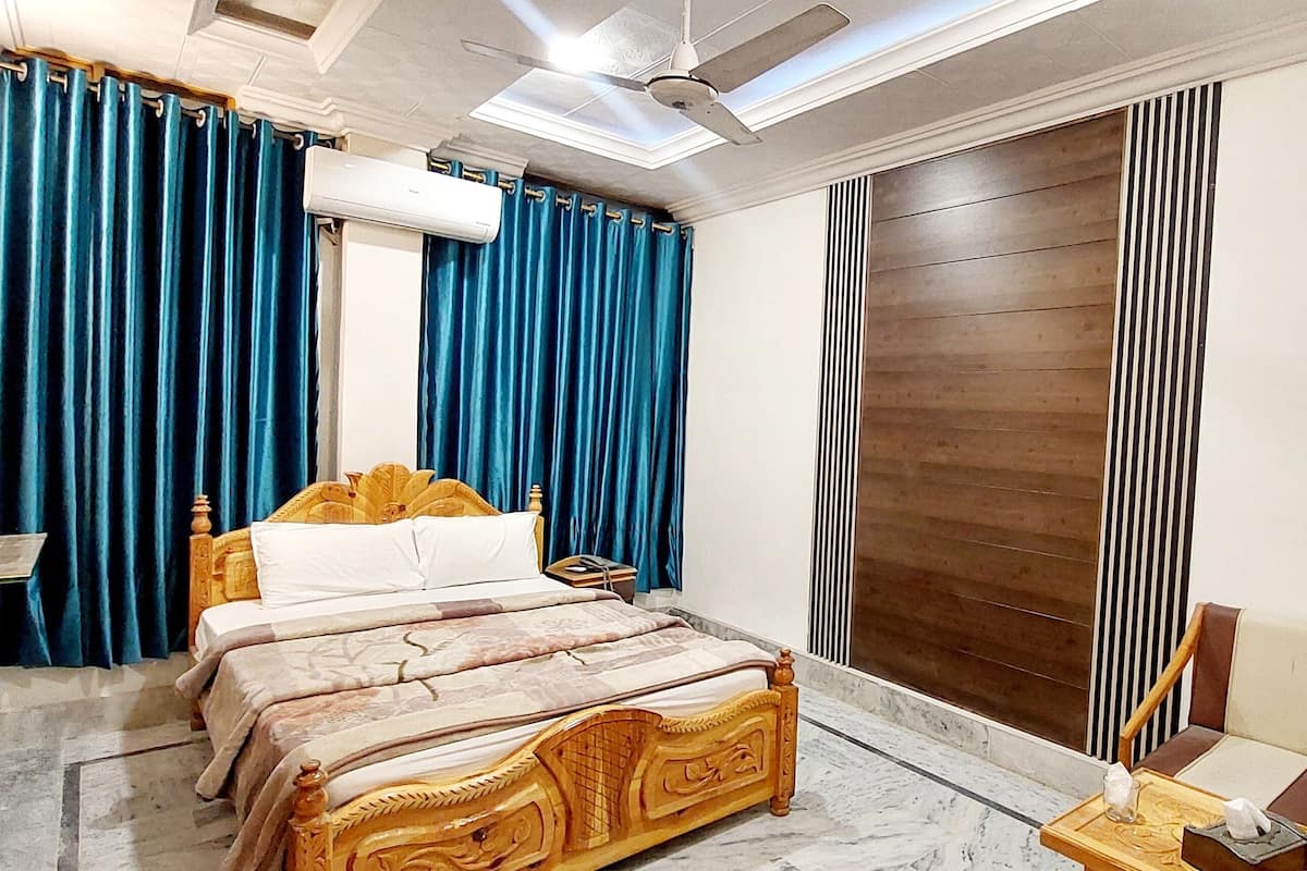 Un dormitorio con cama de madera, cortinas azules, un equipo de aire acondicionado y un ventilador de techo.