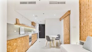 Una cocina moderna con una isla central, un área de comedor con dos sillas y una cama con un almohadón.
