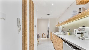 Una cocina moderna con lavavajillas integrado, cafetera y detalles de madera en los armarios.