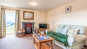 A cozy living room with a fireplace, a television, a sofa, and a coffee table. - Bunloit Combi by Interhome (Drumnadrochit)