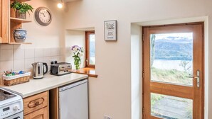 A kitchen with a skylight, a view of the outdoors, and a door leading outside. - Bunloit Combi by Interhome (Drumnadrochit)