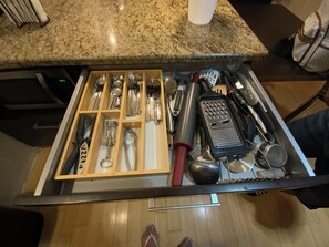 A drawer with kitchen utensils, a grater, and a coffee cup on a granite countertop. - 2-bedroom apartment in charming Clearwater with cool AC (Clearwater)