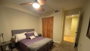 Un dormitorio con cama, ventilador de techo, armario y puerta que da a otra habitación.