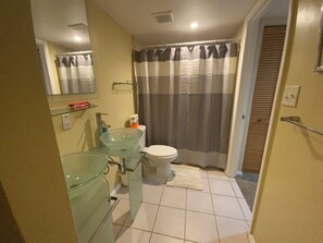 Un bagno con lavabo in vetro, WC e tenda doccia.