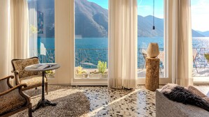 Ein Zimmer mit Blick auf einen See und Berge, ein runder Tisch, eine Couch und ein dekorativer Baumstumpf.