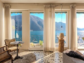 Ein Zimmer mit Blick auf einen See und Berge, ein runder Tisch, eine Couch und ein dekorativer Baumstumpf.