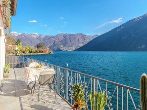 Eine Terrasse mit Tisch und Stühlen mit Blick auf einen See, im Hintergrund Berge.