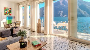 Ein geräumiges Zimmer mit einer großen Schiebeglastür, die auf einen Balkon mit Seeblick und Bergblick führt.