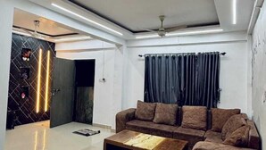 A modern living room with a sectional sofa, a coffee table, and recessed lighting. - Ananya Holidays Villa (Lonavala)